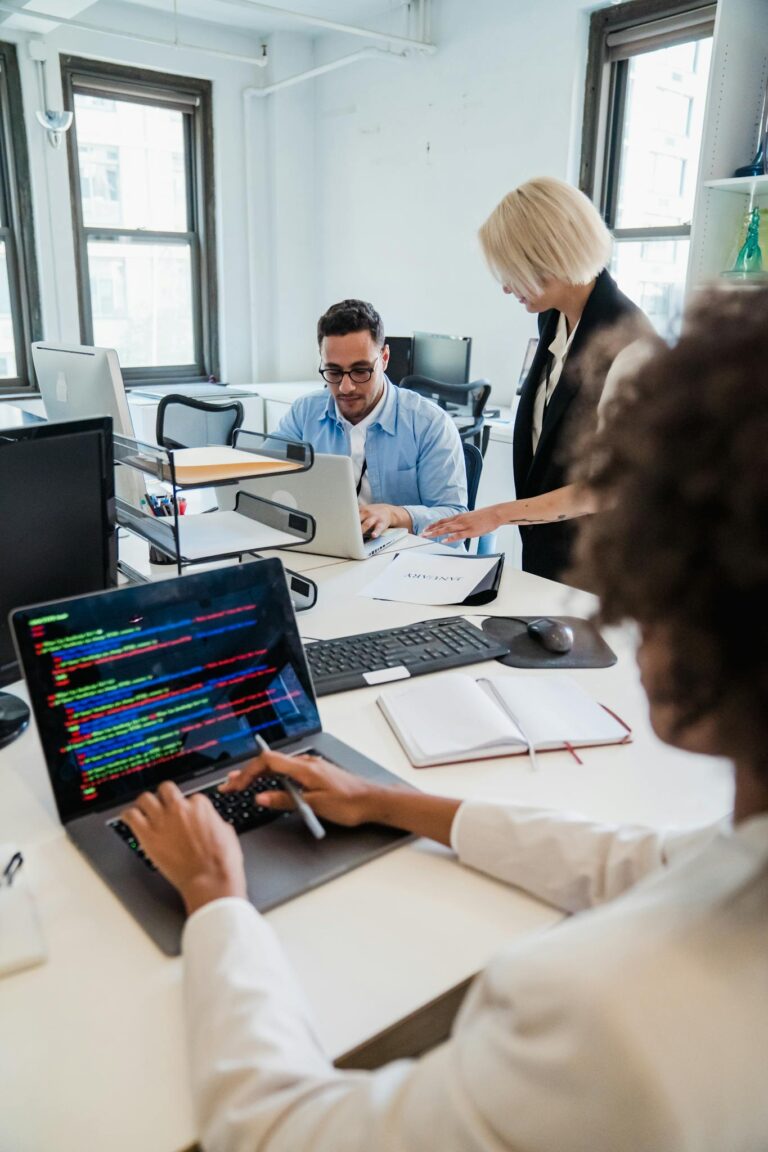 Team of professionals collaborating in a modern office, focused on coding and project management.